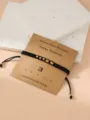 Black braided Morse code number bracelet with gold metal beads on kraft display card for daily wear. - Morse Code 3 Black Flat Knot Bracelet with Card
