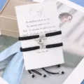 Κοντινό πλάνο μαύρων πλεγμένων βραχιολιών ζευγαριού με μαγνητική καρδιά σε κάρτα. - Μαύρο (1 Ζευγάρι) / Κάρτα Παρουσίασης Επίπεδος Κόμπος Μαγνητική Καρδιά