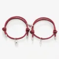 Detail shot of magnetic couple bracelets featuring red braided rope, lock, and key charms. - Key Lock Wine Red Pair