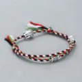 Close-up of handmade woven rope bracelet with Buddha head alloy beads and colorful threads. - Buddha Head Hand Rope F7 (Red White Black Green)