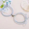 Close up view of matching couple braided rope bracelets featuring magnetic heart attraction charm. - Elastic Heart Magnet Style / 1 Pair / Light Blue