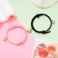 Detailed view of couple magnetic matching heart bracelets with winged charm, pink and black. - Magnetic Heart Pair / 1 Pair / Black and Pink