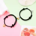 Close-up detail of black rope couple bracelets with magnetic heart charms and cute wing locks. - Magnetic Heart Pair / 1 Pair / Black