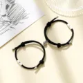 Detailed view of black braided cord couple bracelets featuring magnetic sun and moon charms. - Milan Cord Sun Moon Black Pair