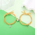 Gedetailleerd overzicht van stijlvolle koppelarmbanden van geel gevlochten touw met hart. - Slot Sleutel Stijl (Gembergeel Paar)