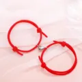 Close-up detail of the matching red string couple bracelets with magnetic metal heart clasp. - Minimalist Red Pair