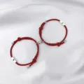 Detail view of magnetic couple bracelets featuring red black woven cord and sun moon charms. - Sun & Moon / 2-Piece Set / Black Red