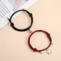 Close up of magnetic couple braided bracelets with cute smiley face pendants. Detail shot. - One Pair / Black and Wine Red