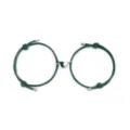 Close-up detail of magnetic couple heart bracelet set with green braided rope and charms. - Dark Green Pair