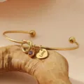 Détail de bracelet jonc nœud d'amour en acier doré avec pierre de naissance. - Or / Pierre de Naissance d'Octobre