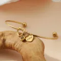 Détail de bracelet jonc doré en acier inoxydable avec nœud cœur et charm pendentif gravé Love. - Or / Pierre de Naissance de Novembre