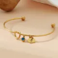 Detail de bracelet jonc en acier dore avec pierre de naissance bleue et charm coeur. - Or / Pierre de Naissance de Décembre