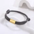 Detailed view of the dark grey woven cord bracelet with a polished gold metal tube. - Silver Accessory / Dark Gray Paracord