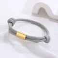 Detail shot of gray paracord woven bracelet featuring a sleek gold metal tube component. - Gold Accessory / Light Gray Paracord