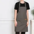 Grey canvas bib apron with adjustable 3-snap neck strap and large front utility pockets. - Dark Gray