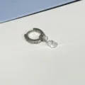 Detailaufnahme eines funkelnden Zirkon-Creolen-Ohrrings mit wunderschönem Kristallanhänger. - Weiß