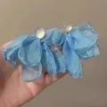 Nahaufnahme blauer, transparenter Stoff-Ohrringe mit eleganter Feen-Ästhetik für den Urlaub. - Transparenter Kopf Blumen / Blauer Stoff