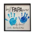 Detailed view of DIY wooden handprint father's day gift sign with blue hand prints and text. - Papa