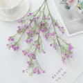 Detailed close-up view of artificial purple baby breath flower branch with green leaves. - Fuschia