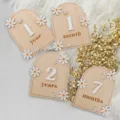 Wooden baby milestone cards detail view with daisy decor and monthly number photo props. - Main Style