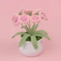 Close-up detail of a handmade crochet pink daisy potted plant on a solid pink background - Pink Daisy (MENGSI) / Pink