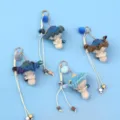 Detailed view of colorful handmade crochet mushroom pendants with fluffy pompoms and beads - Blue