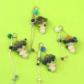 Detailed view of four handmade crochet mushroom keychains on a vibrant green background - Green