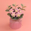 Detailansicht von handgefertigten rosa Häkelblumen in einem rosa geriffelten Keramiktopf - Rosa