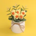 Handgehäkelte Puffblumen im weißen Keramiktopf mit einer rustikalen Juteschleife - Gelb