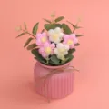 Detailansicht von handgefertigten rosa und weißen Häkelblumen in einem stilvollen Blumentopf - Verlauf Rosa