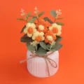 Handgehäkelte Puffblumen in einem weißen Keramiktopf mit einer Juteschleife - Gradient Orange