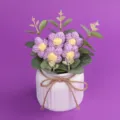 Detailansicht der handgestrickten lila Puffblumen in einem weißen gerippten Keramiktopf - Lila