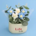 Macro detail of hand-woven crochet puffer flowers in a minimalist cream colored pot - Puff Flower Potted Plant / Gradient Blue