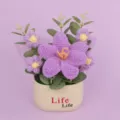 Detailed macro view of handmade purple crocheted flower arrangement in a cream ceramic pot - Purple