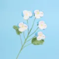 Detailed view of hand-knitted crochet pansy flowers on a light blue background - Blue