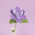 Exquisite detail of a handmade crochet purple magnolia flower set in a white ceramic vase - Purple