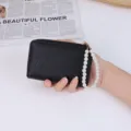 Elegant black lychee pattern short wallet featuring a stylish white pearl wrist strap - Black
