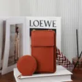 Orange pebble grain leather phone bag with wide patterned strap and round coin purse. - Brown