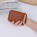 Stylish small brown litchi grain wallet featuring an elegant pearl beaded wristlet strap - Brown