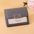 Detailansicht einer stilvollen kleinen Damen-Geldbörse in Grau und Beige mit Metallschnalle. - Grau