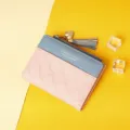 Detail view of the pink embossed pattern and heart tassel charm on a small wallet - Pink