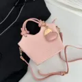 Elegante borsa a secchiello in PU rosa pitonato con ciondolo a cuore e manici annodati - Rosa