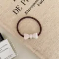 Detailed macro view of a brown elastic hair tie with a white bow ornament - Bowknot Style / Pearl White