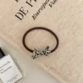 Detail view of a brown elastic hair tie with a stylish leopard print bow ornament. - Ribbon Style / Black White Dots