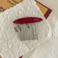 Close-up of red acetate hair comb with gold FRANCE Handmade lettering and metal teeth - Red