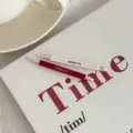 Κοντινό πλάνο με μινιμαλιστικά τσιμπιδάκια μαλλιών σε κόκκινο και κρεμ πάνω σε διακοσμητικό φόντο - Εξαιρετική Συσκευασία / Σετ 2 τεμαχίων / Κόκκινο + Λευκό