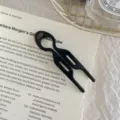 Detail view of a black acetate U-shaped hair fork shown on an elegant recipe background - Black - Large