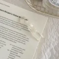 Close-up detail of a pearlescent acetate fish-shaped U-pin hair fork on a printed book - Pearlescent White - Small