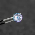 Macro-weergave van 6mm reuzenradgeslepen gradiënt oorsteker vastgehouden door pincet - Roestvrij Stalen Externe Spiraal Kraakbeen Piercing (A1150) / Blauw Paars