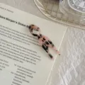 Close-up of a small fish-shaped acetate U-pin hair fork with a marble pattern on a book. - Light Leopard - Small